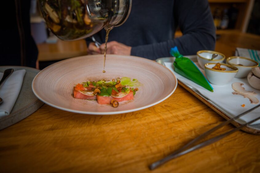 Chef Scott Davies pours the forest tea over the rainbow trout.