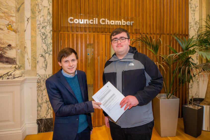 Xander McDade receives the petition from Bobby Brian inside the Perth and Kinross Council building.