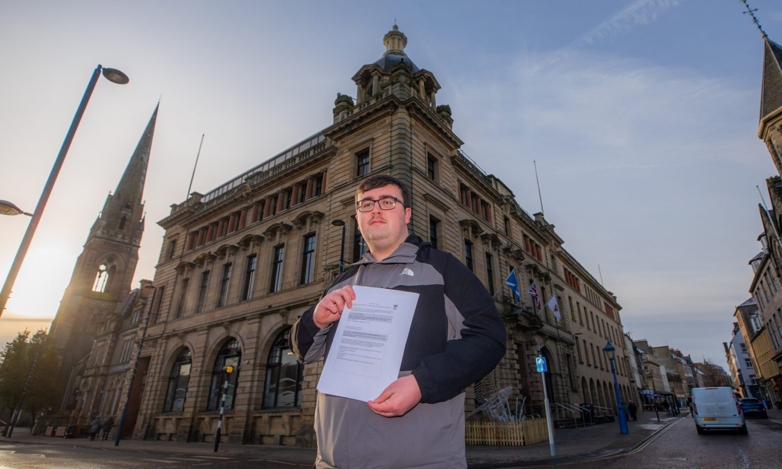 Bobby Brian holds the petition and stands in from of Perth and Kinross Council building.