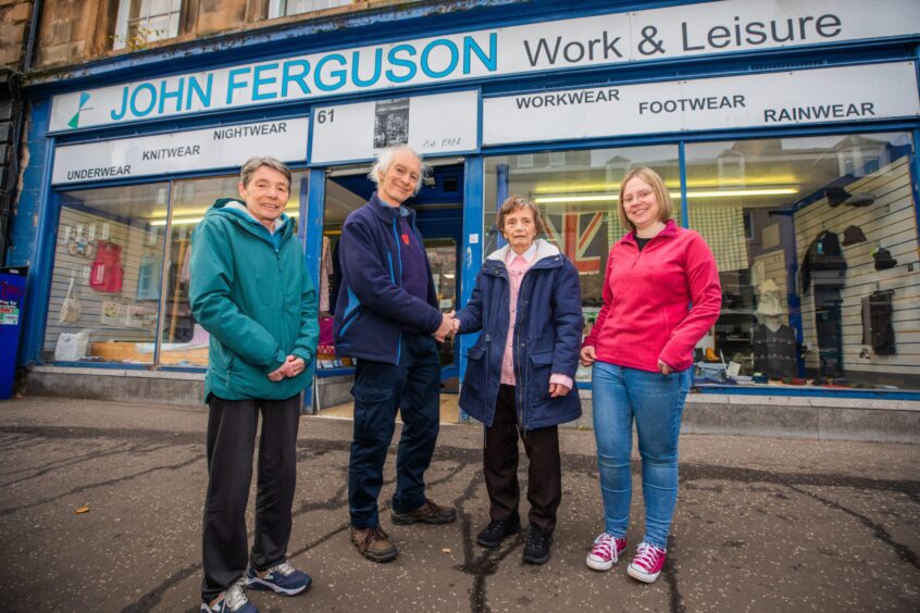 Betty shaking hands with John Ferguson outside the shop with her daughter and granddaughter standing either side