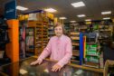 Betty Shakespeare behind counter at John Ferguson shop in Perth. Behind her are old fashioned wooden shelves full of clothing