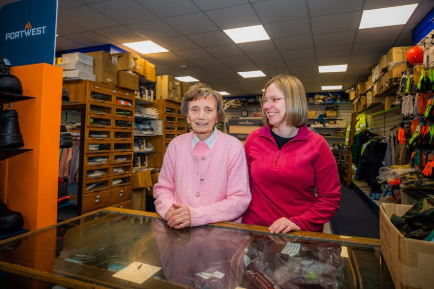 Betty and granddaughter Kirsty behind counter in old fashioned clothes shop