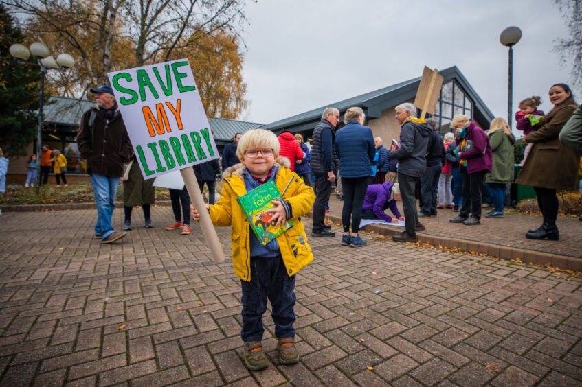 Small boy holding 'save my library' placard