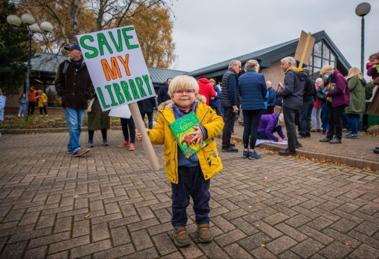 Small boy holding 'save my library' placard