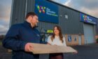 Marie STorrie and Steven Lawrie holding plank of wood in front of Perth branch of Wooden Floor Store