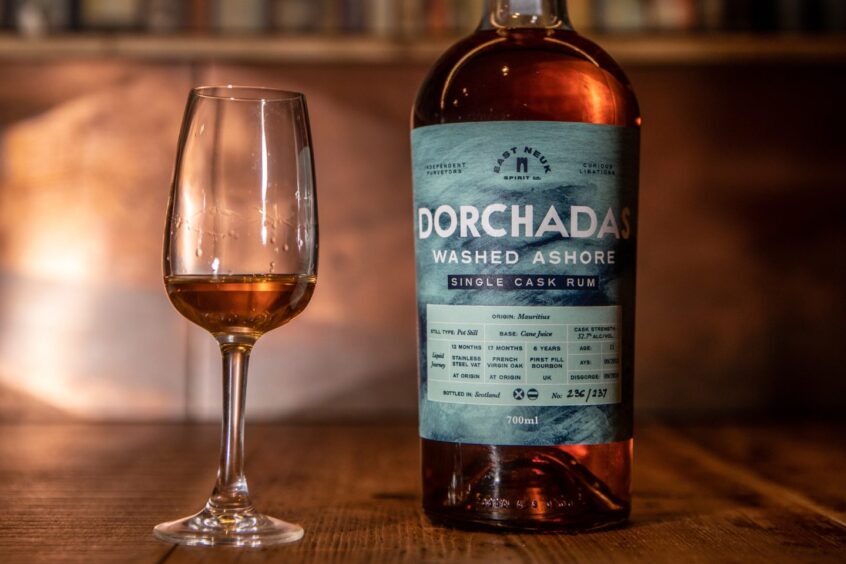 a bottle of Dorchadas single cask rum and a small amount in the glass next to it.