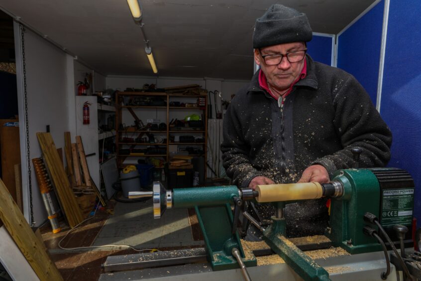 Image shows a man turning wood in a workshop in St Andrews.