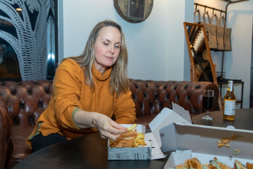 Rachel eating her fish a chips inside Lindores Abbey Distillery.