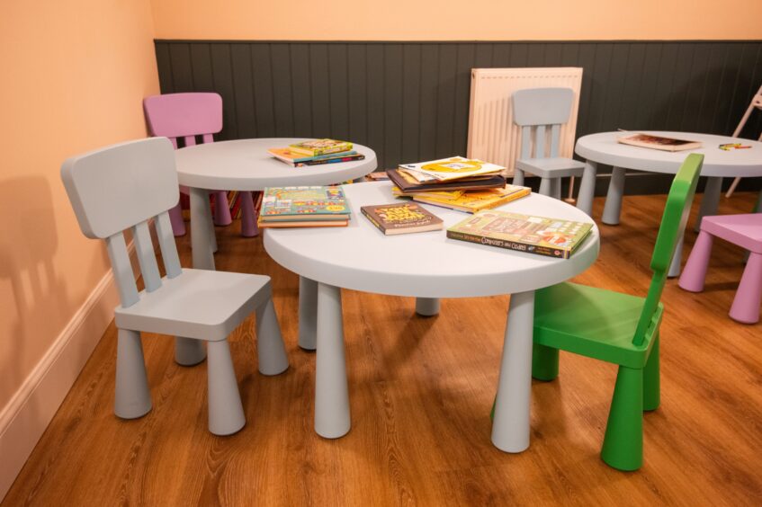 A kids area in the cafe with small tables and chairs and toys.