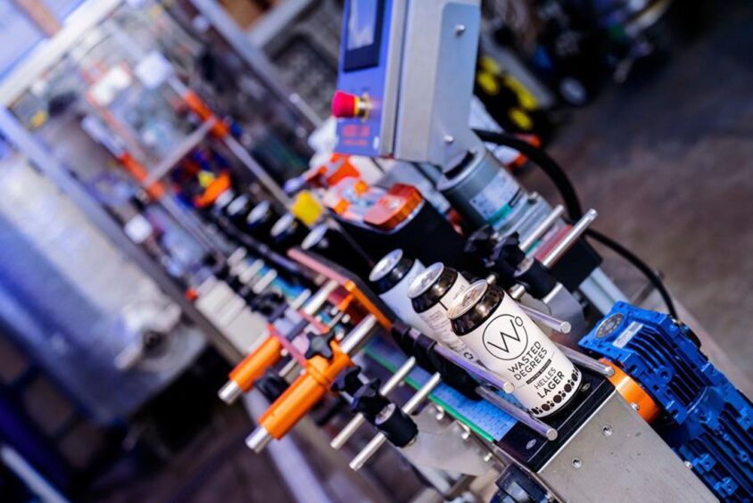 cans of Wasted Degrees lager on production line.