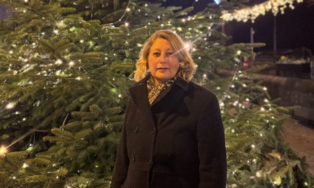 Avril Douglas stands in front of a lit up tree.