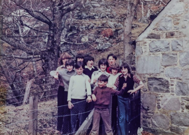 kids pose for a picture beside a stone building while on a trip to Kinloch Rannoch for the 12-14 age group at Easter 1979. 