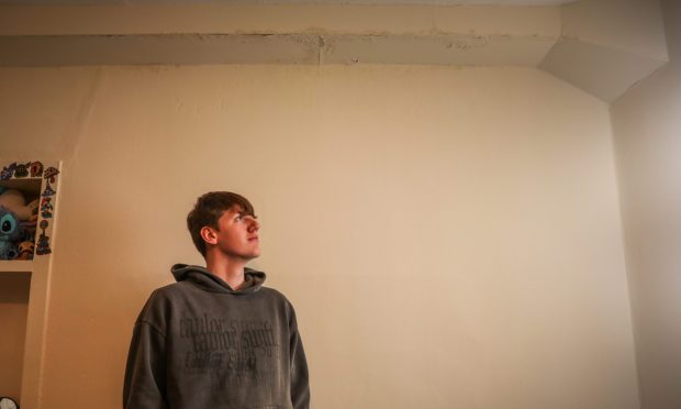 Jamie Daniels in his Dundee flat where water regularly pours in. Image: Mhairi Edwards/DC Thomson