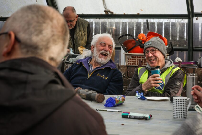 Image shows two St Andrews Men's Shed members sharing a joke during a coffee break.