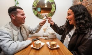 Two customers smiling and enjoying themselves as they eat their crumble inside Sweetpea Cafe.