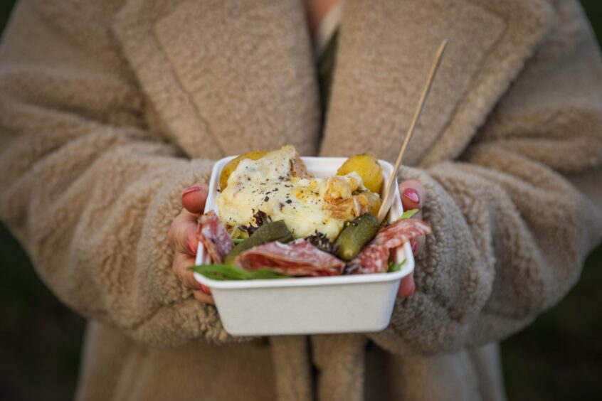 Rachel holding a portion of the raclette dish.