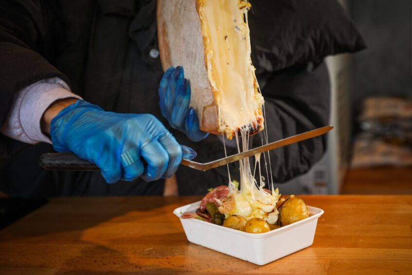 Kate slicing the melted cheese onto the hot potatoes and salad.