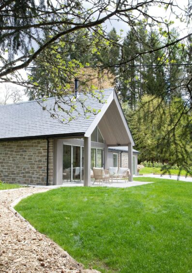 Stone and timber house front surrounded by trees