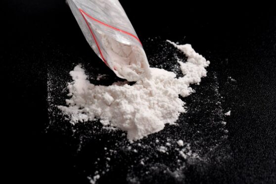 Cocaine in plastic package sprinkled on black background. Illustration of illegal drug substances, narcotics; Shutterstock ID 2476510351; purchase_order: Tele ; job: Front