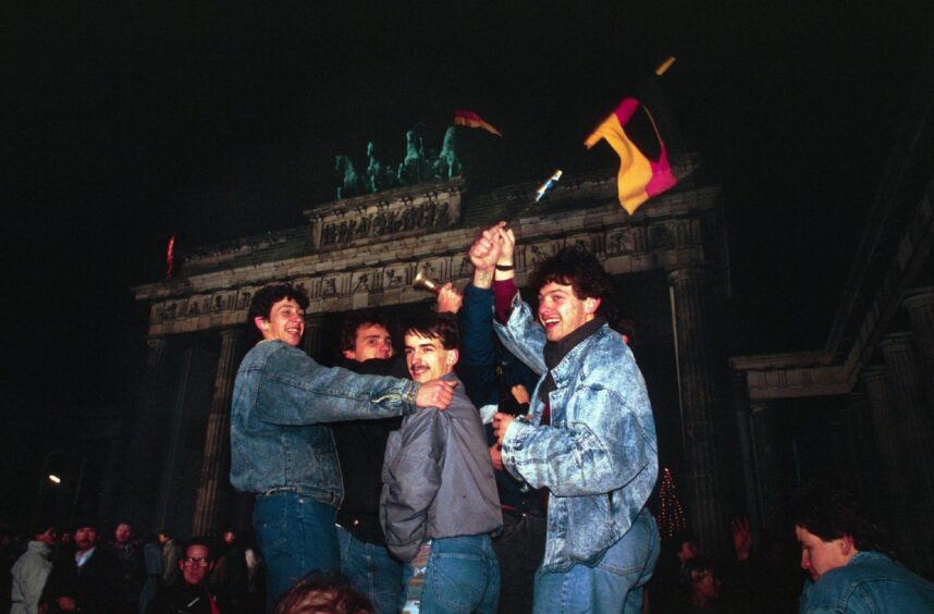 Berliners waving flags at the Brandenburg Gate celebrate the fall of the wall in November 1989. 