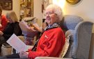 Jenny White seated in armchair holding birthday card