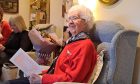 Jenny White seated in armchair holding birthday card