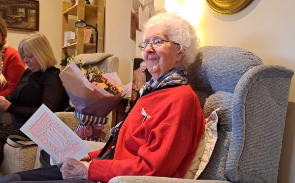 Jenny White seated in armchair holding birthday card