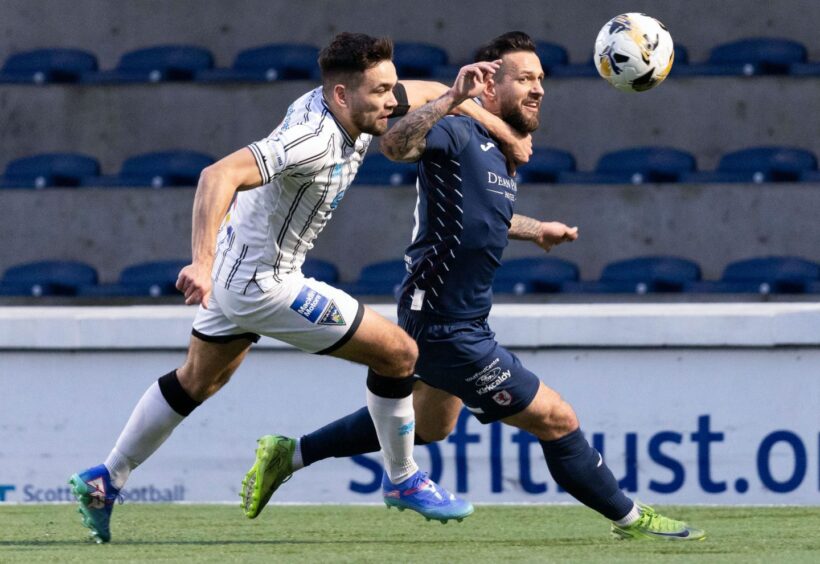 Dunfermline Athletic defender Aaron Comrie uses his left arm to hold off Raith Rovers opponent Dylan Easton as they tussle for the ball.