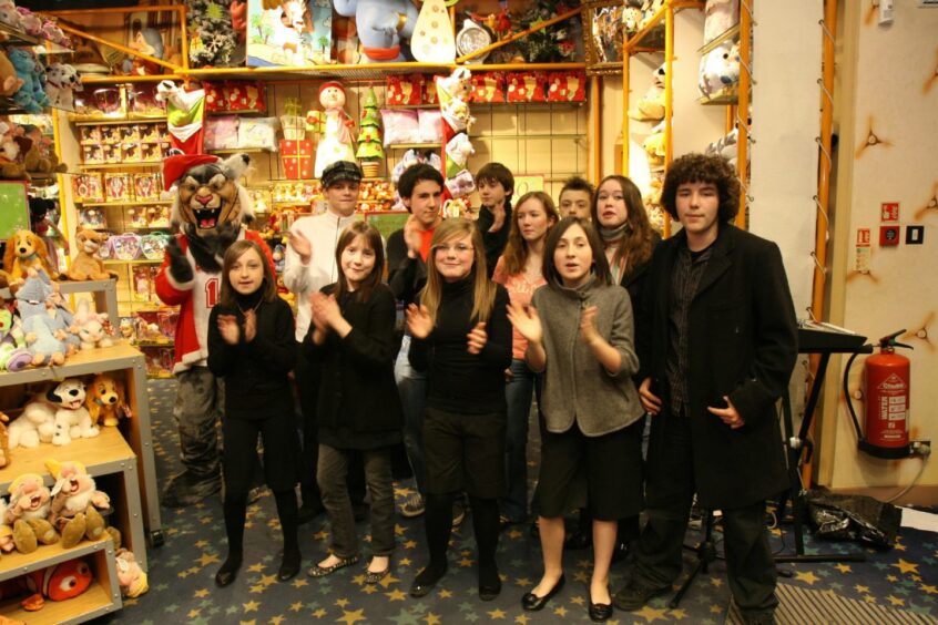 Tread the Boards cast members singing in the Disney Store. 