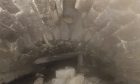 Drone footage showing pile of stones beneath hole in arched masonry