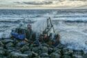 The stranded fishing boat being pounded by the waves near Arbroath.