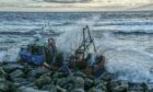 The stranded fishing boat being pounded by the waves near Arbroath.