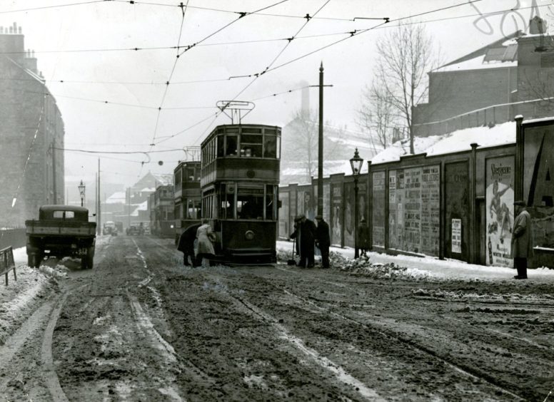 People snow clearing in front of a tram in Main Street in Dundee. 