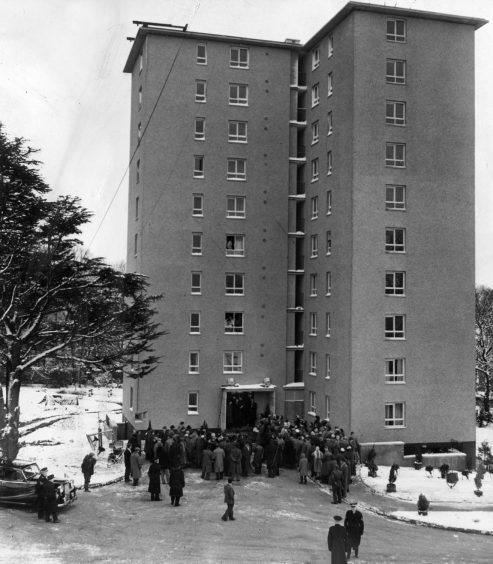 Snow on the ground as people gather at the entrance for the opening ceremony at the main door of the first block. 