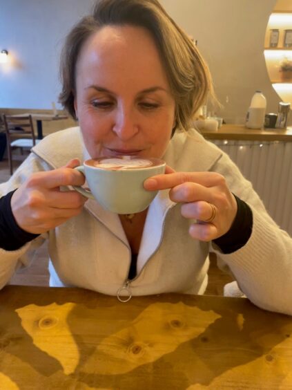 A woman drinking a small cup of hot chocolate.