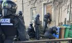 Police raiding a house in Cairn Street East, Kirkcaldy, with officers at the front door and in the garden