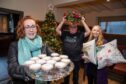 Hazel Lightbody with two other people holding a tray of mincemeat pies and Christmas wreath