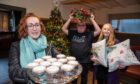 Hazel Lightbody with two other people holding a tray of mincemeat pies and Christmas wreath