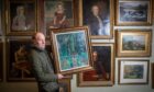 Nick Burns holding oil painting in front of wall of paintings