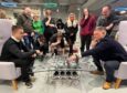 Group of people watching man and teenage boy play chess on set made from old Porsche parts at Y Centre in Perth