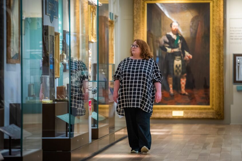 Helen Smout walking past display case in Perth Museum