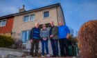 Pete Wishart standing outside two storey house with two men and a woman.