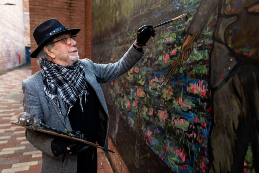 Ian Imrie with paintbrush beside new artwork in centre of Perth