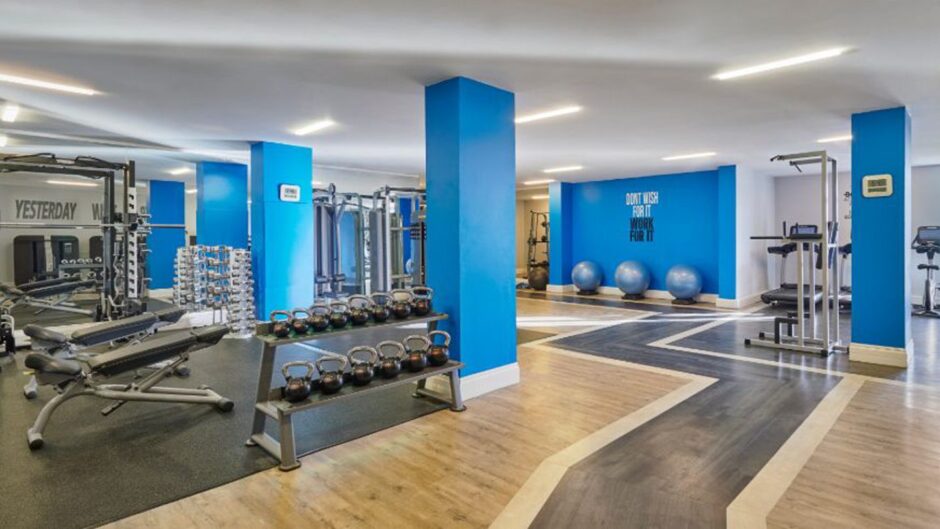 the interior of the The Fairmont Hotel gym, which has blue pillars and an array of equipment