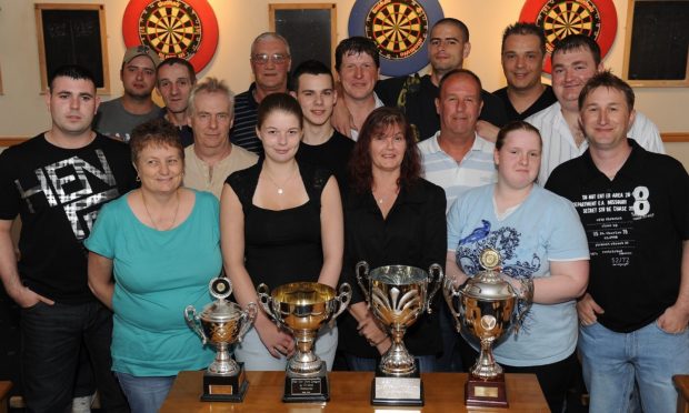 Perth darts players line up for a picture behind a table holding trophies