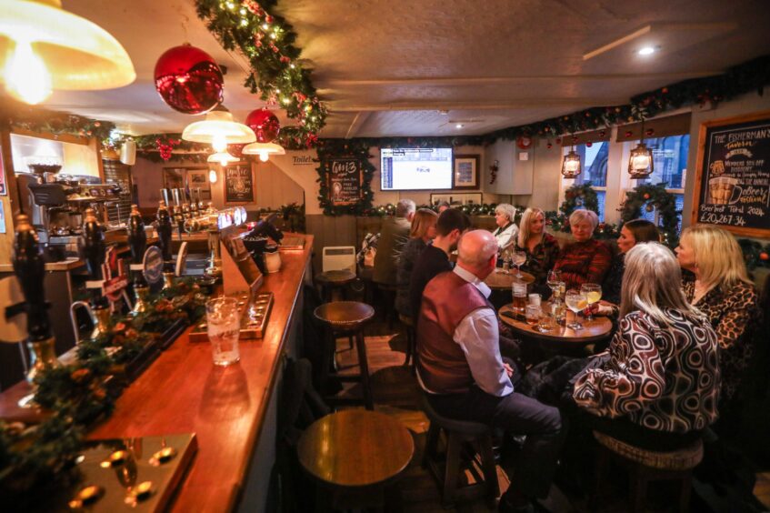 The bar in The Fisherman's Tavern is a lively pub in Broughty Ferry, with drinkers seated at tables. 