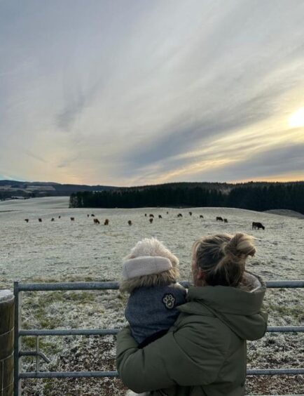 Allen visited with dog Kona. She is pictured holding the dog up to look at cattle in a field