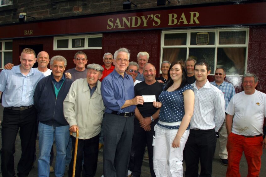 people stand outside the Lochee pub for a cheque presentation as Sandy's Bar donated £1,050 to CHAS in 2006.