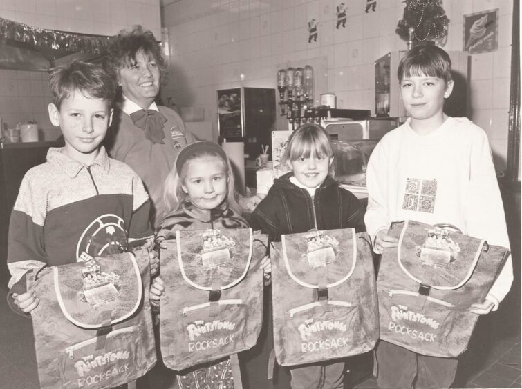 four Flintstones prize-winners hold their new rucksacks with Jessie Murray in 1995.