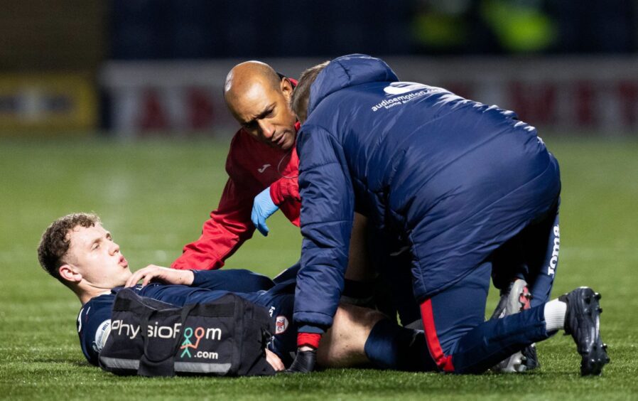 Raith Rovers striker Jack Hamilton lies on the pitch getting medical treatment.